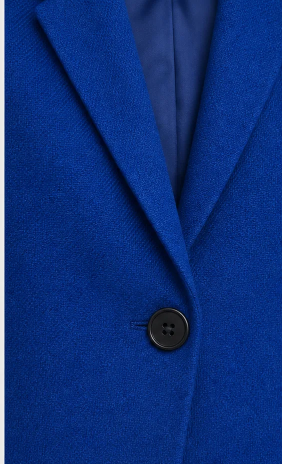 Close detail product image of a structured blazer showing lapel and button construction